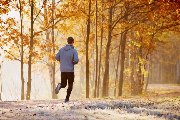 Man running in park during sunny autumn morning. Healthy lifestyle concept
