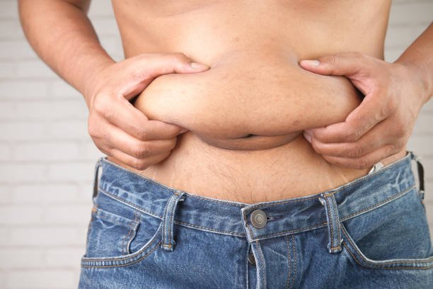 man's hand holding excessive belly fat, overweight concept.